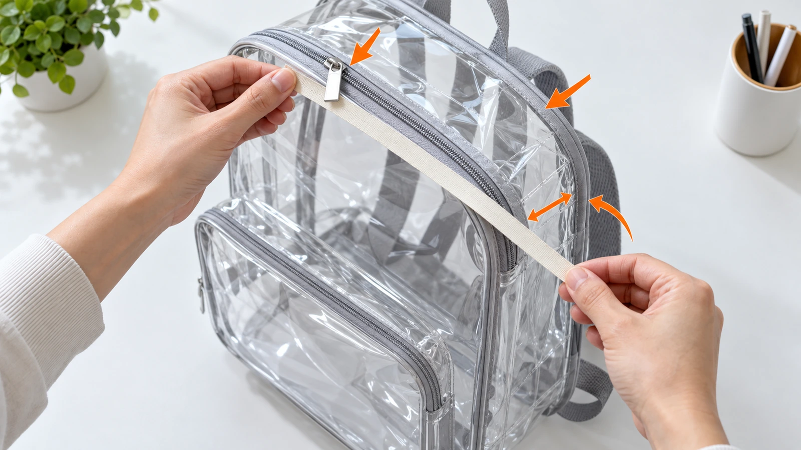 Manos midiendo con una cinta métrica sencilla la altura exterior, la anchura y la profundidad del fuelle de una mochila de PVC transparente, con flechas que muestran que los tiradores de cremallera y el ribete cuentan para el tamaño
