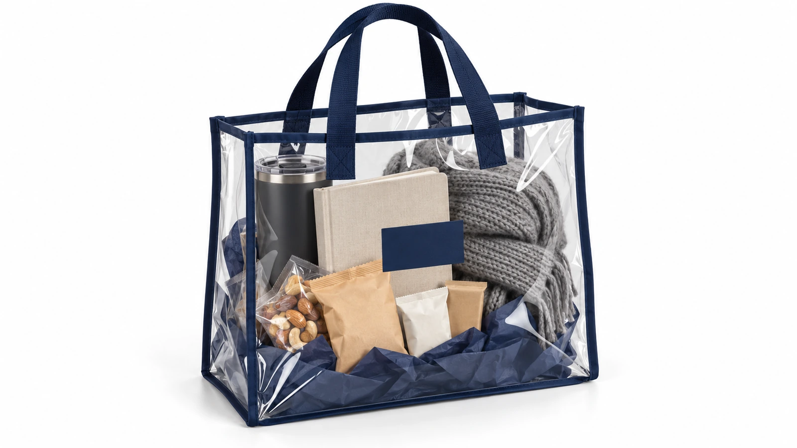 Bolsa de asas de PVC transparente con ribete azul marino que contiene un kit de regalo corporativo seleccionado con un vaso térmico, un cuaderno, tentempiés y una bufanda doblada, todo visible a través de la bolsa