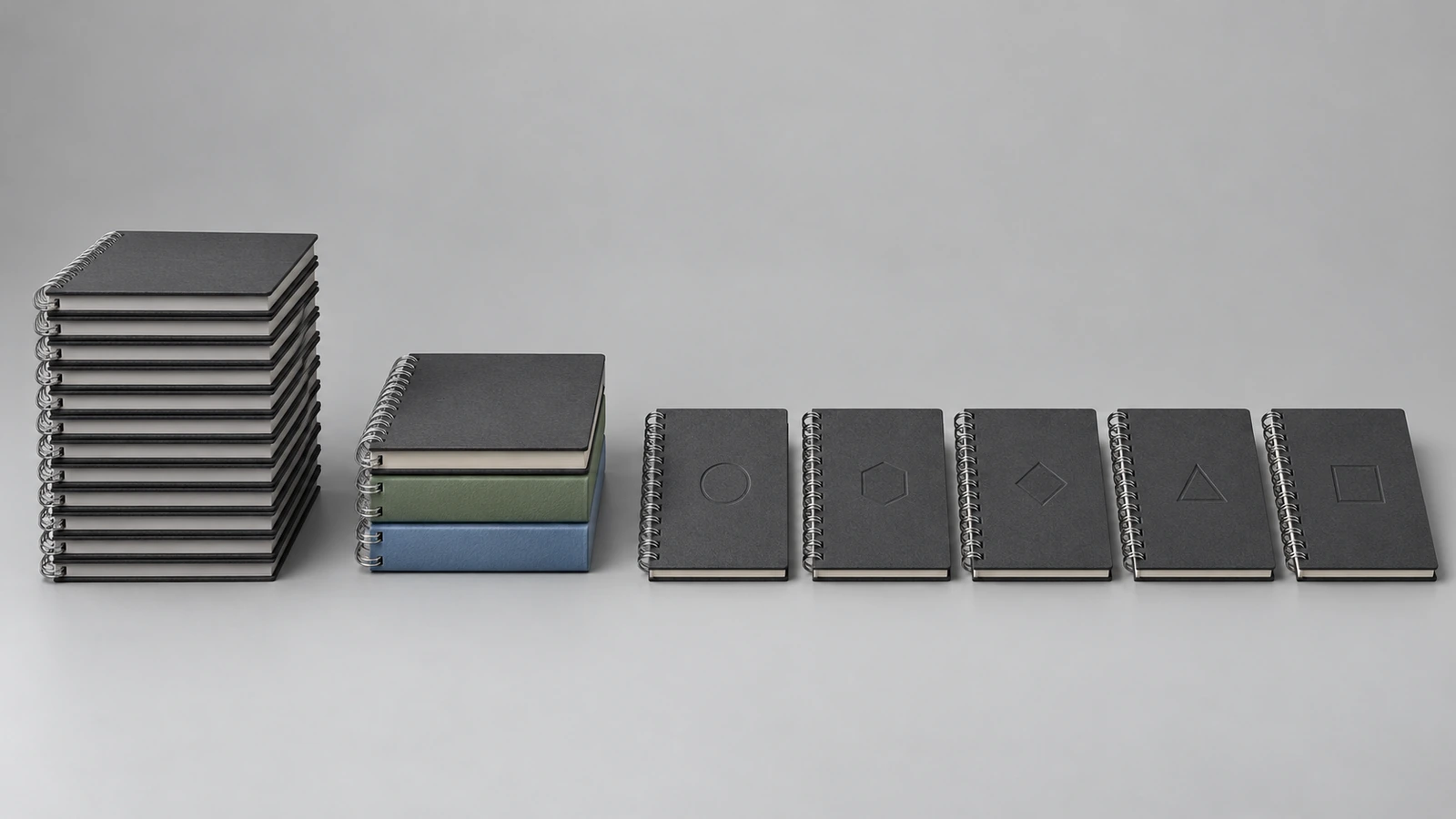 Tres grupos de cuadernos con encuadernación de alambre que muestran una personalización creciente: una pila idéntica, una pila dividida en tres colores de cubierta y una fila de cuadernos marcados cada uno con un pequeño emblema distinto