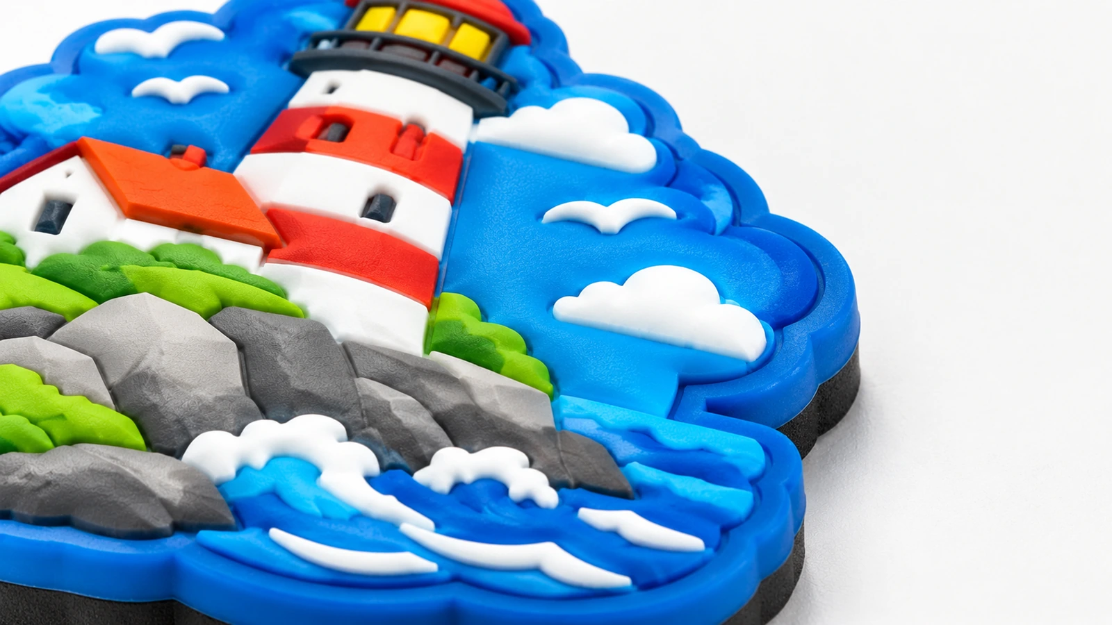 Primer plano de faro en relieve, rocas, olas y detalles de nubes sobre un imán azul