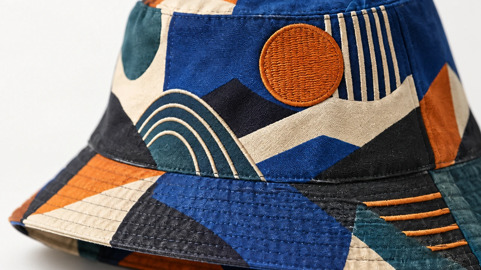 Detalle de la tela y del bordado del bucket hat Primer plano de la tela estampada del bucket hat, del ala cosida y del bordado circular naranja