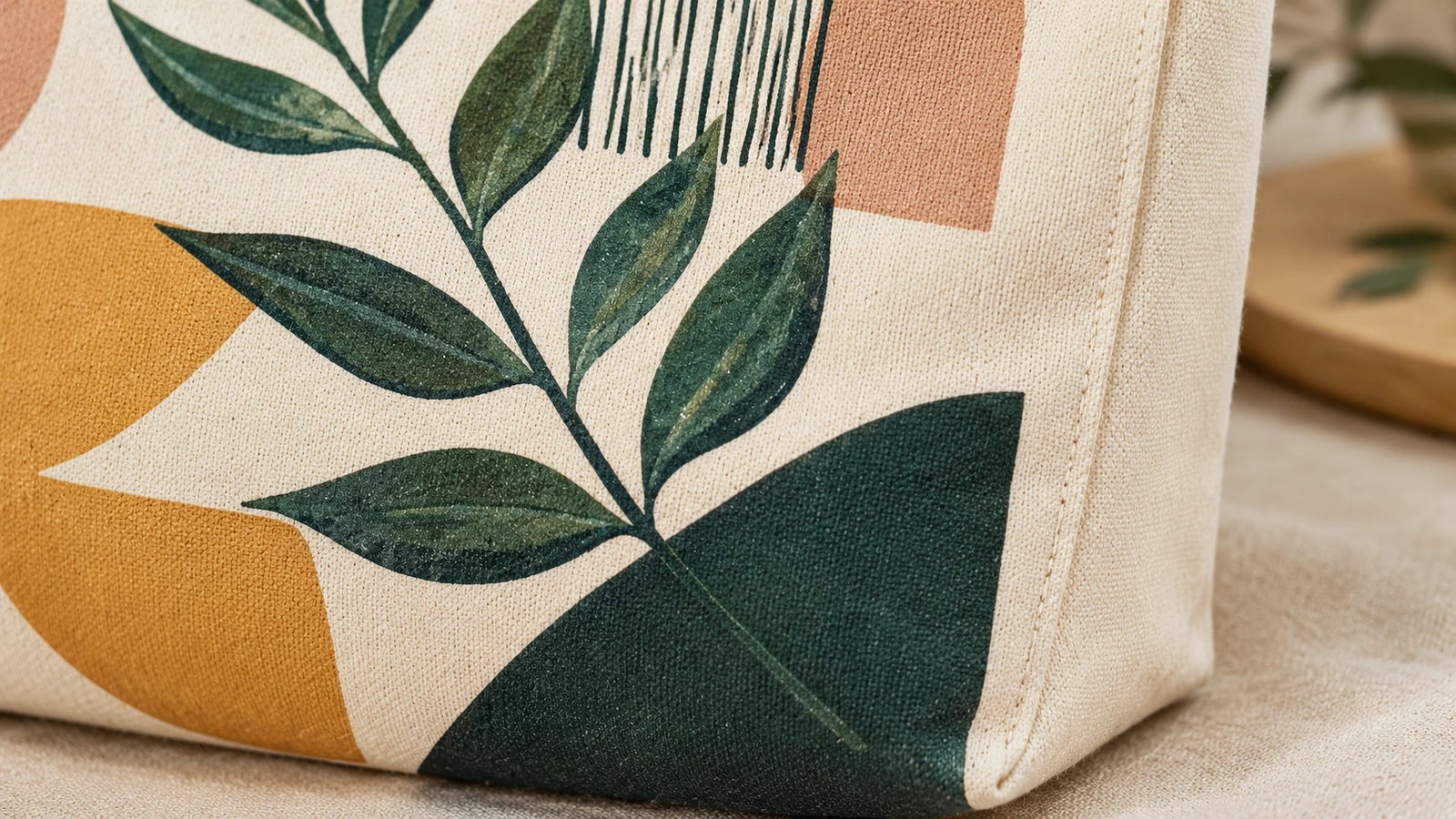 Primer plano de una bolsa tote de lona estampada que muestra el diseño de hojas y un fuelle lateral cosido