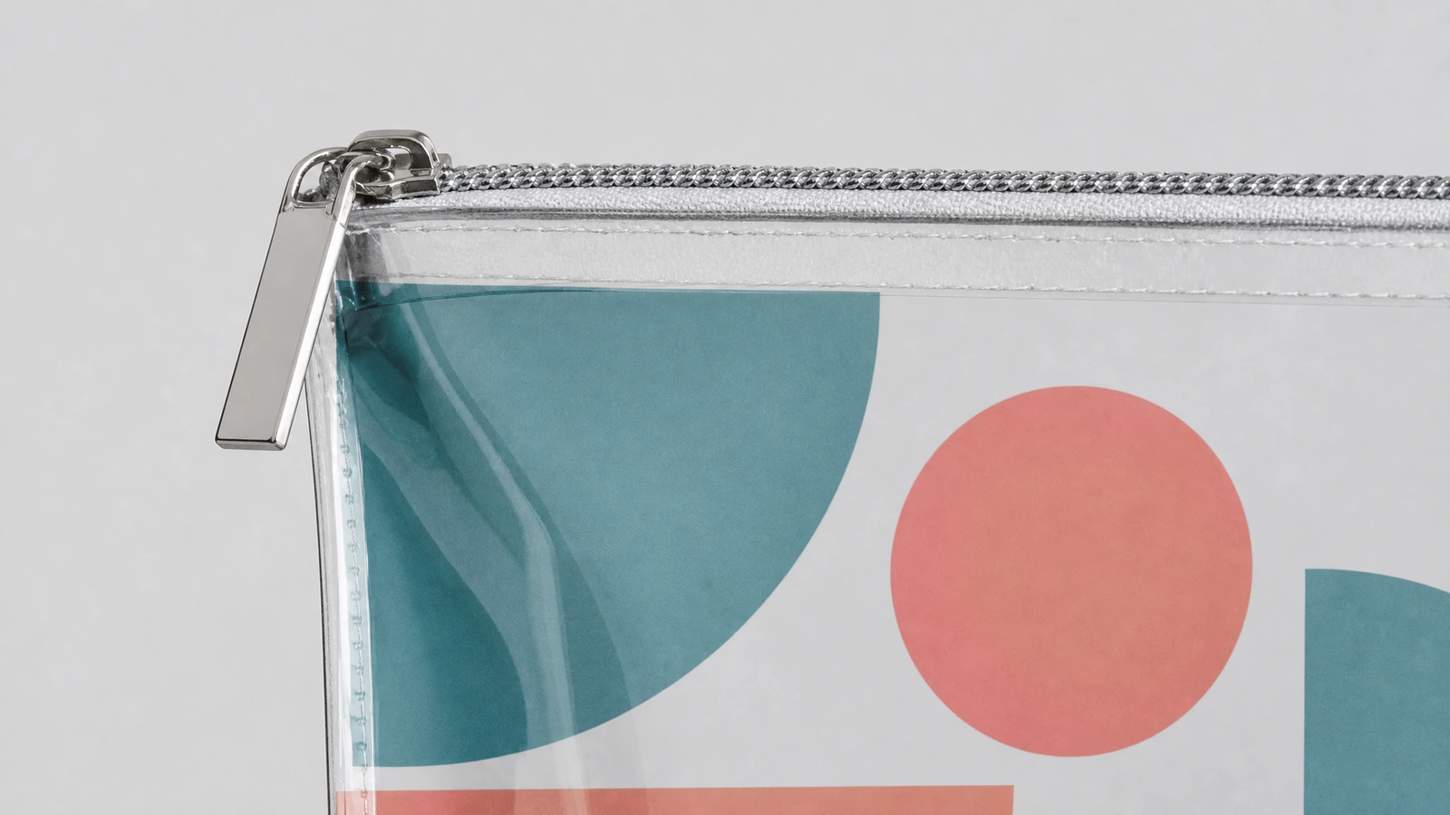 Primer plano de un tirador de cremallera de color plateado y de la esquina de una bolsa transparente impresa