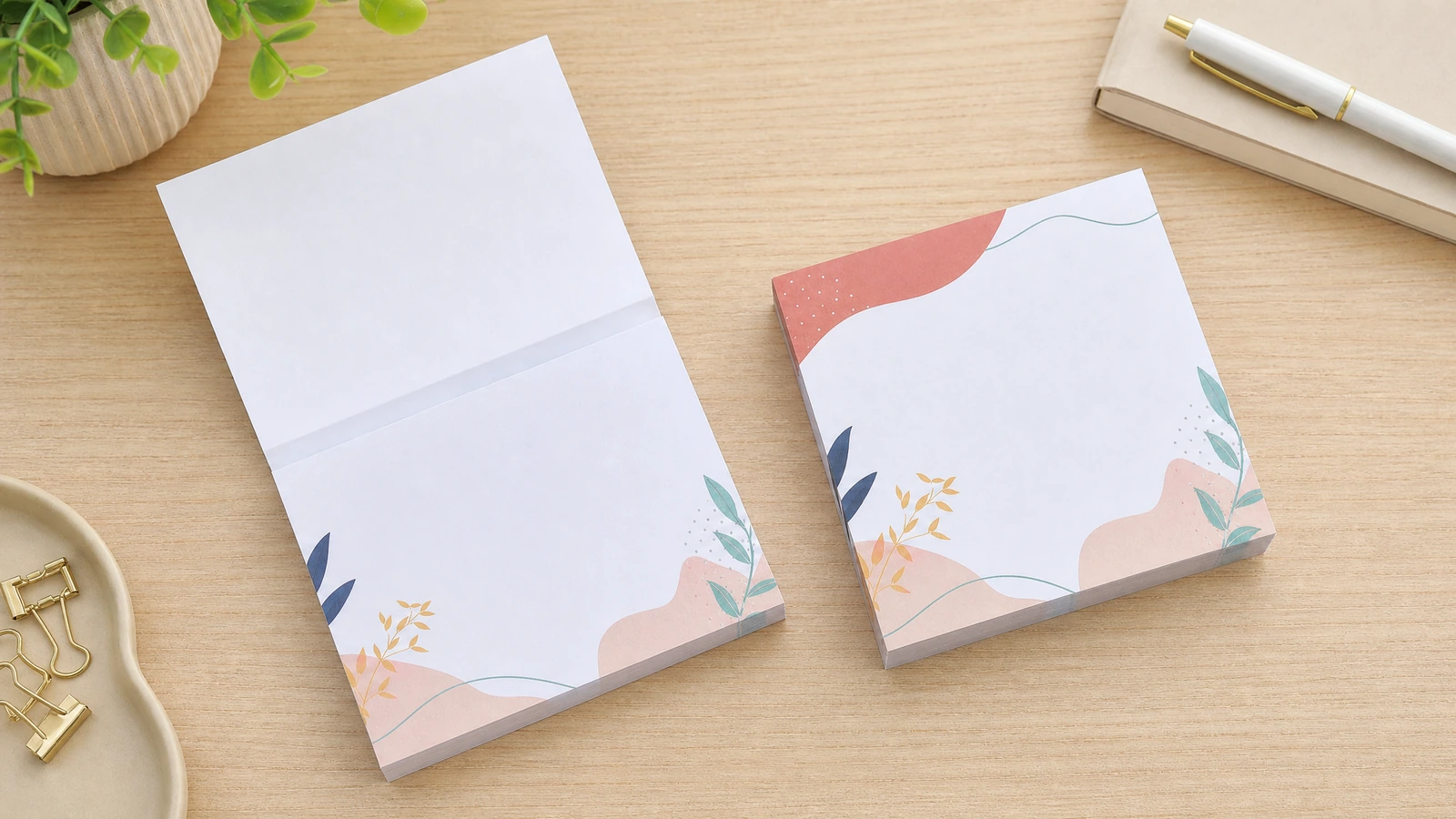 Bloc de notas con motivo floral y una hoja levantada junto a un bloc cerrado a juego