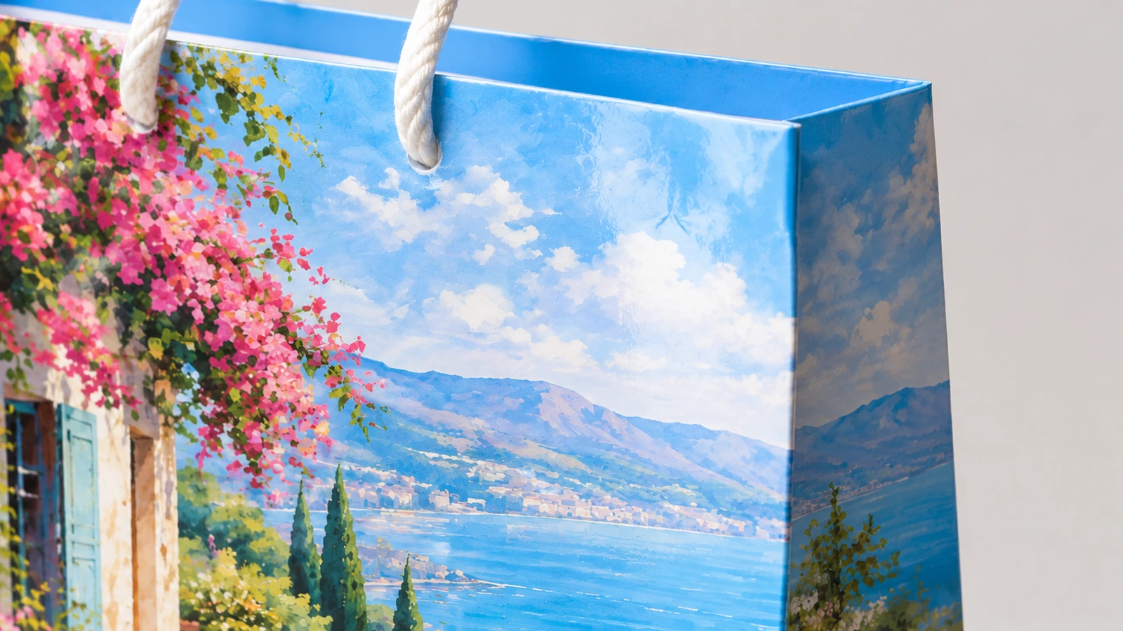 Detalle del estampado de paisaje costero, el pliegue superior azul y el asa de cuerda blanca