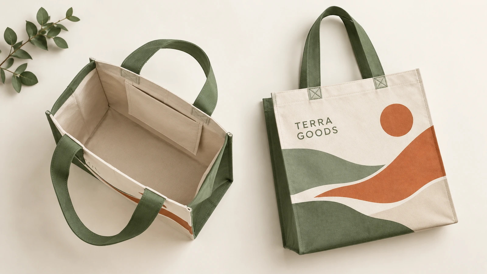 Vistas abierta y de pie de una bolsa tote crema con estampado de paisaje y asas verdes