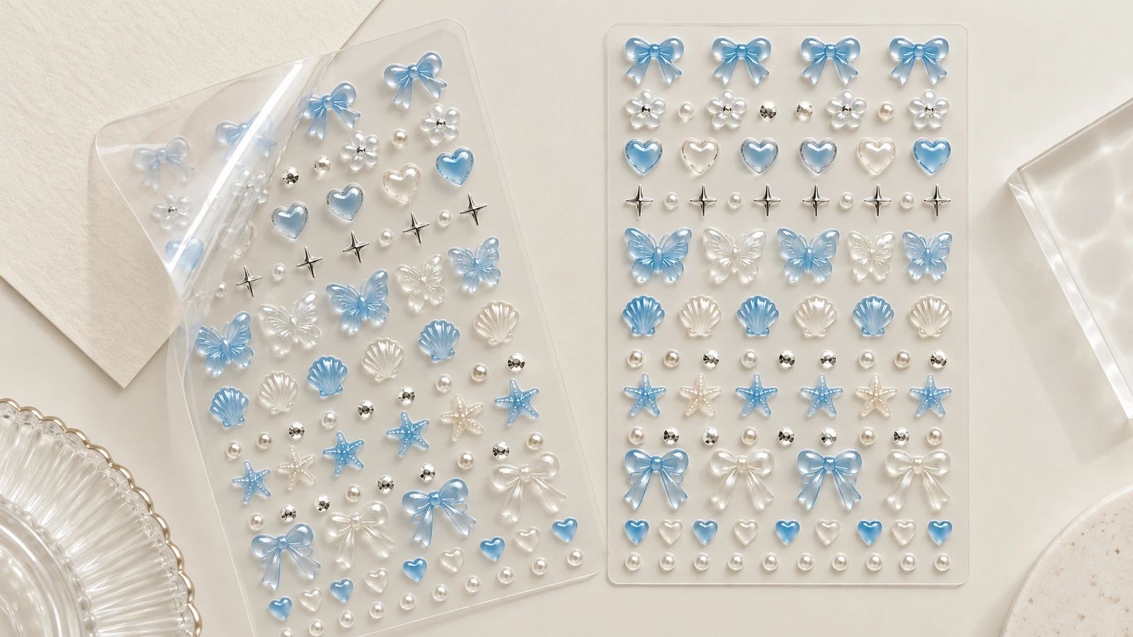 Dos hojas transparentes con lazos azules, corazones, conchas y decoraciones de uñas en color perla