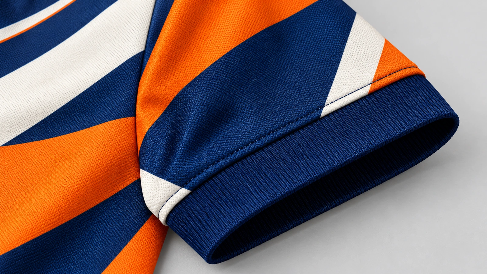 Primer plano de una manga estampada en naranja, azul marino y blanco, con puño de canalé azul marino