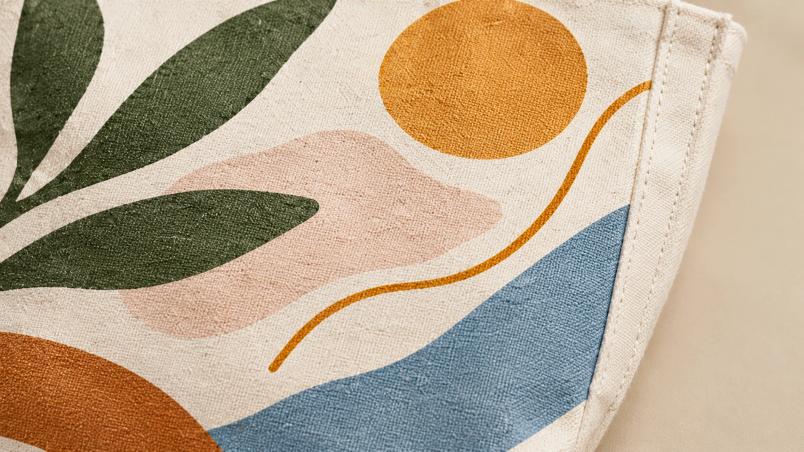 Primer plano del diseño de hoja y motivo abstracto sobre tela de algodón, junto a un borde cosido